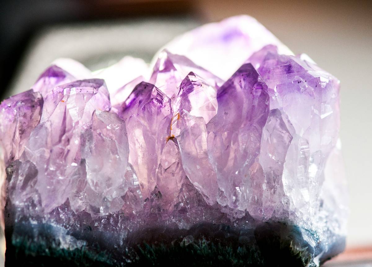 Hand holding a mix of crystals for spiritual protection including Hematite and Amethyst on a wooden surface